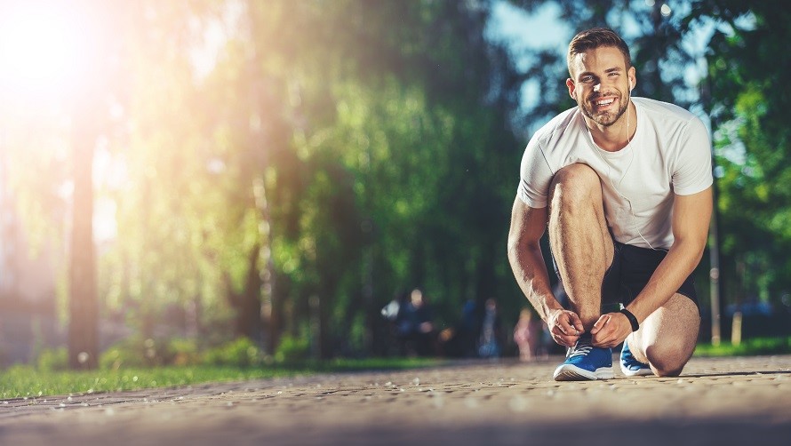 Mann bindet sich die Laufschuhe auf einem Weg im Park Mann bindet sich die Laufschuhe auf einem Weg im Park